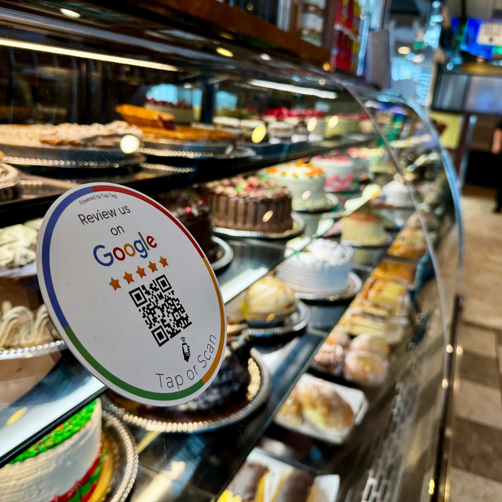 Google review sticker on a bakery display case showcasing a variety of colorful cakes.