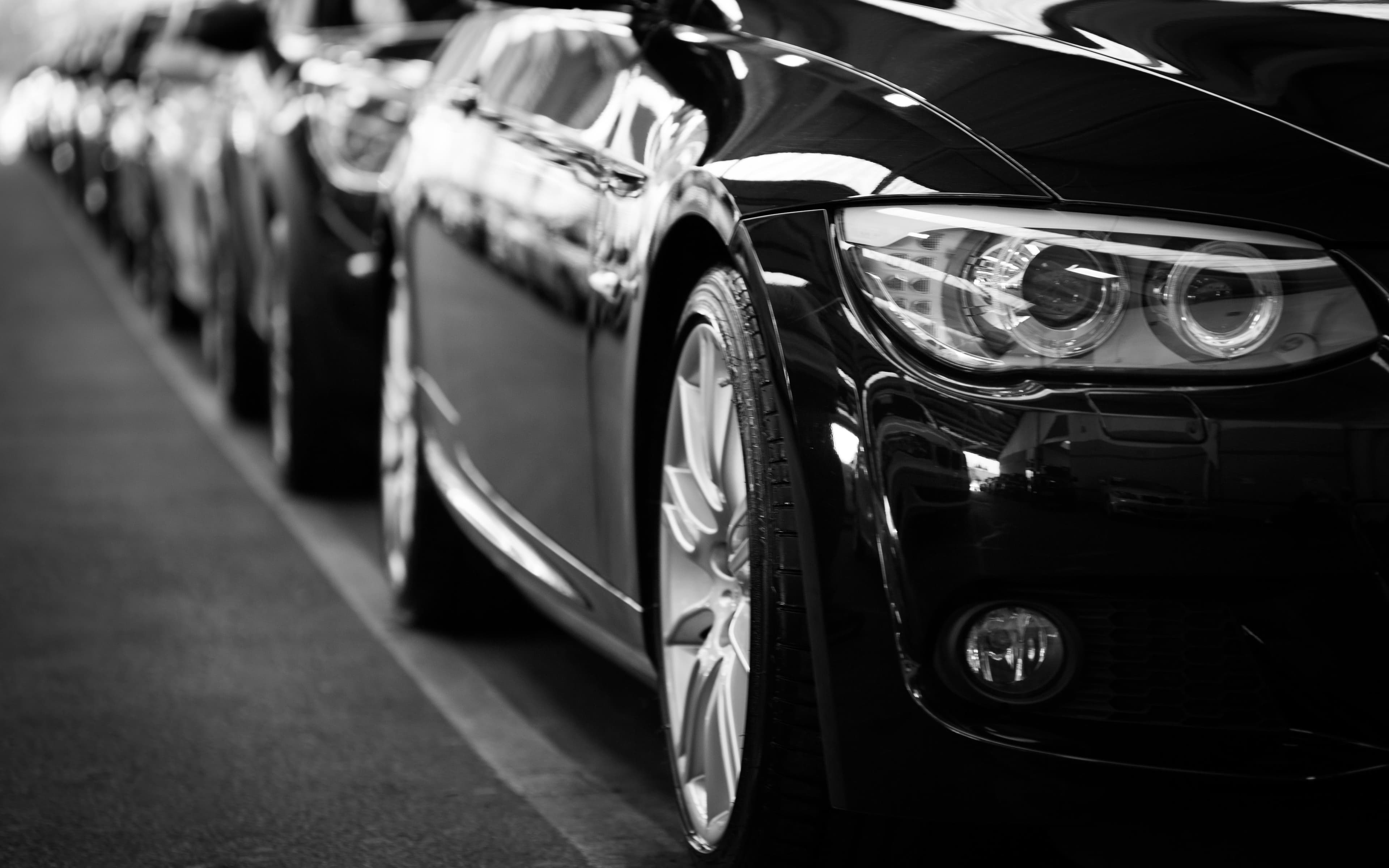 Sleek black luxury cars parked in a row, with a focus on the front headlight.